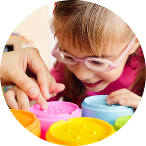girl wearing glasses touching braille blocks